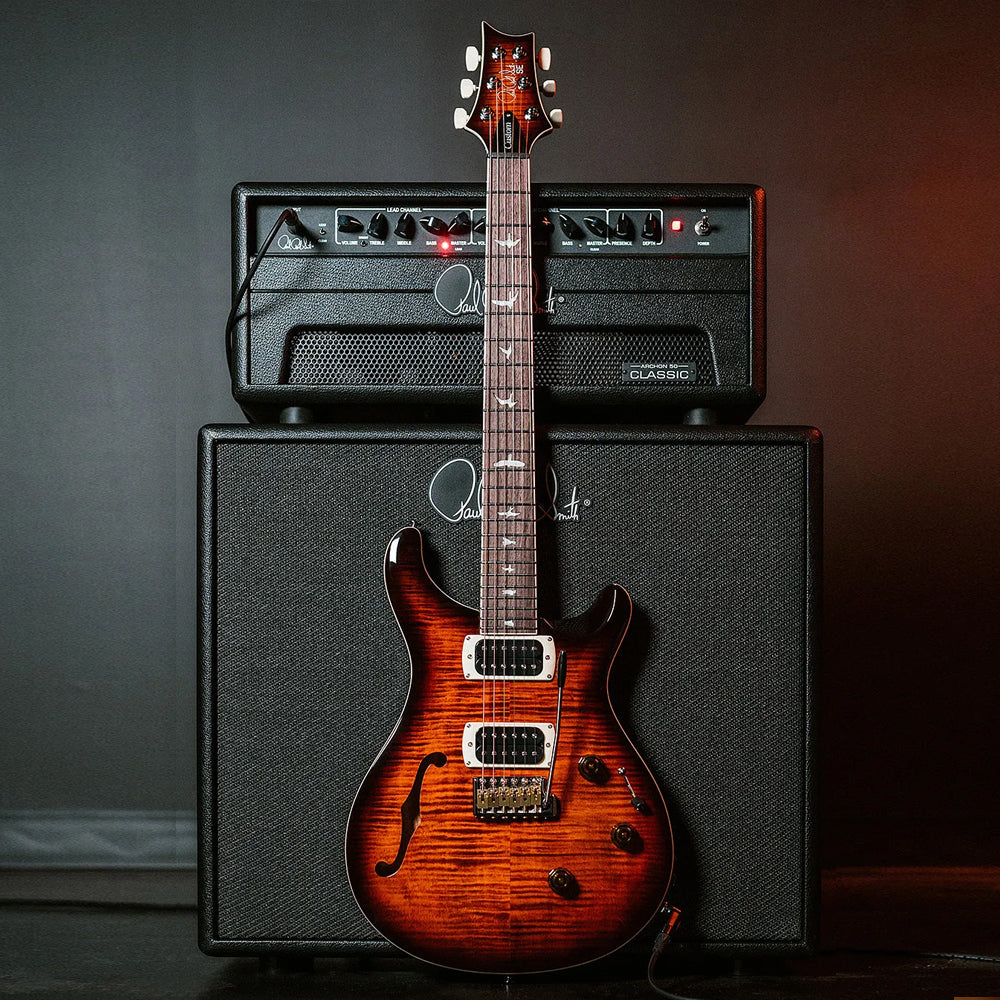 Paul Reed Smith electric guitar leaning on guitar amp head and cabinet