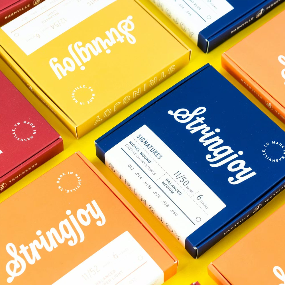 Colorful Stringjoy instrument string packages aligned in a grid on a yellow surface