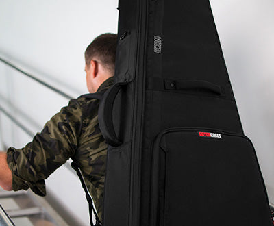 Person walking upstairs with a Gator Cases guitar bag on their back