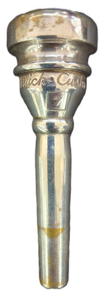 A silver metallic trumpet mouthpiece with engraved text reading 'Rudy Muck' and a size marking of 7.