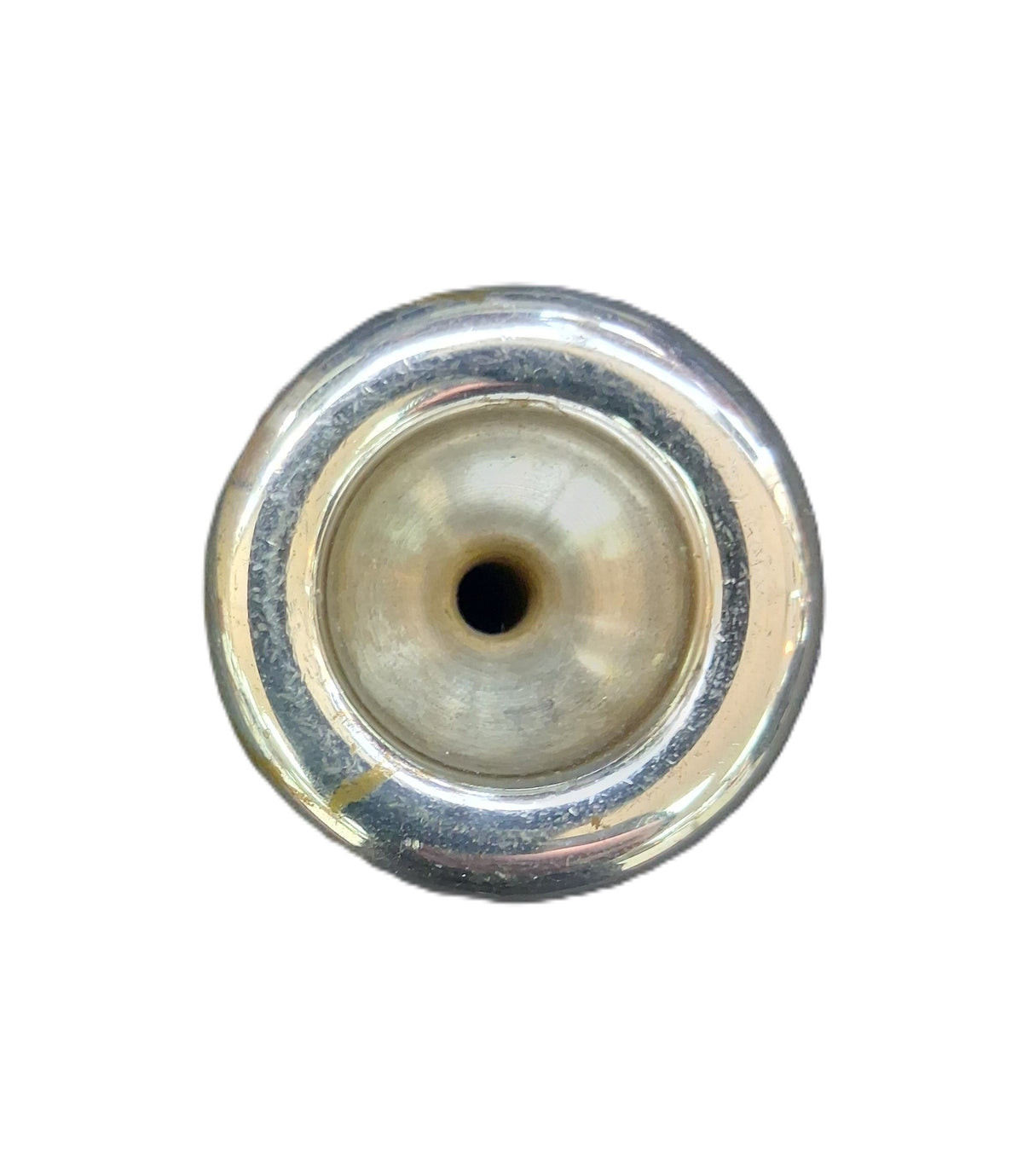 A close-up top-down view of a trumpet mouthpiece with a central hole, showing a polished silver-toned rim