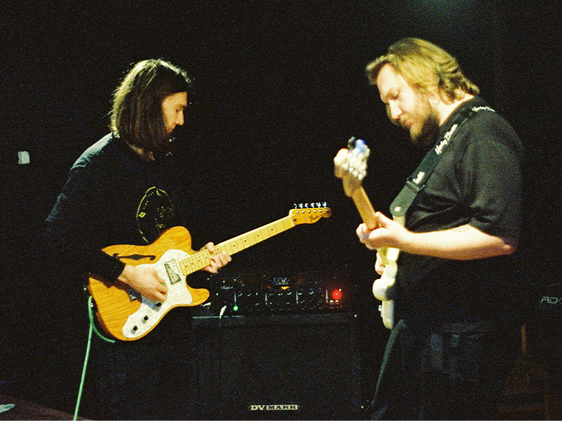 Two guitarists performing together on stage with electric guitars