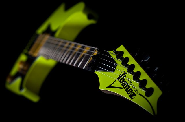 A close-up of a Zennin electric guitar headstock and neck in bright neon yellow-green against a solid black background.