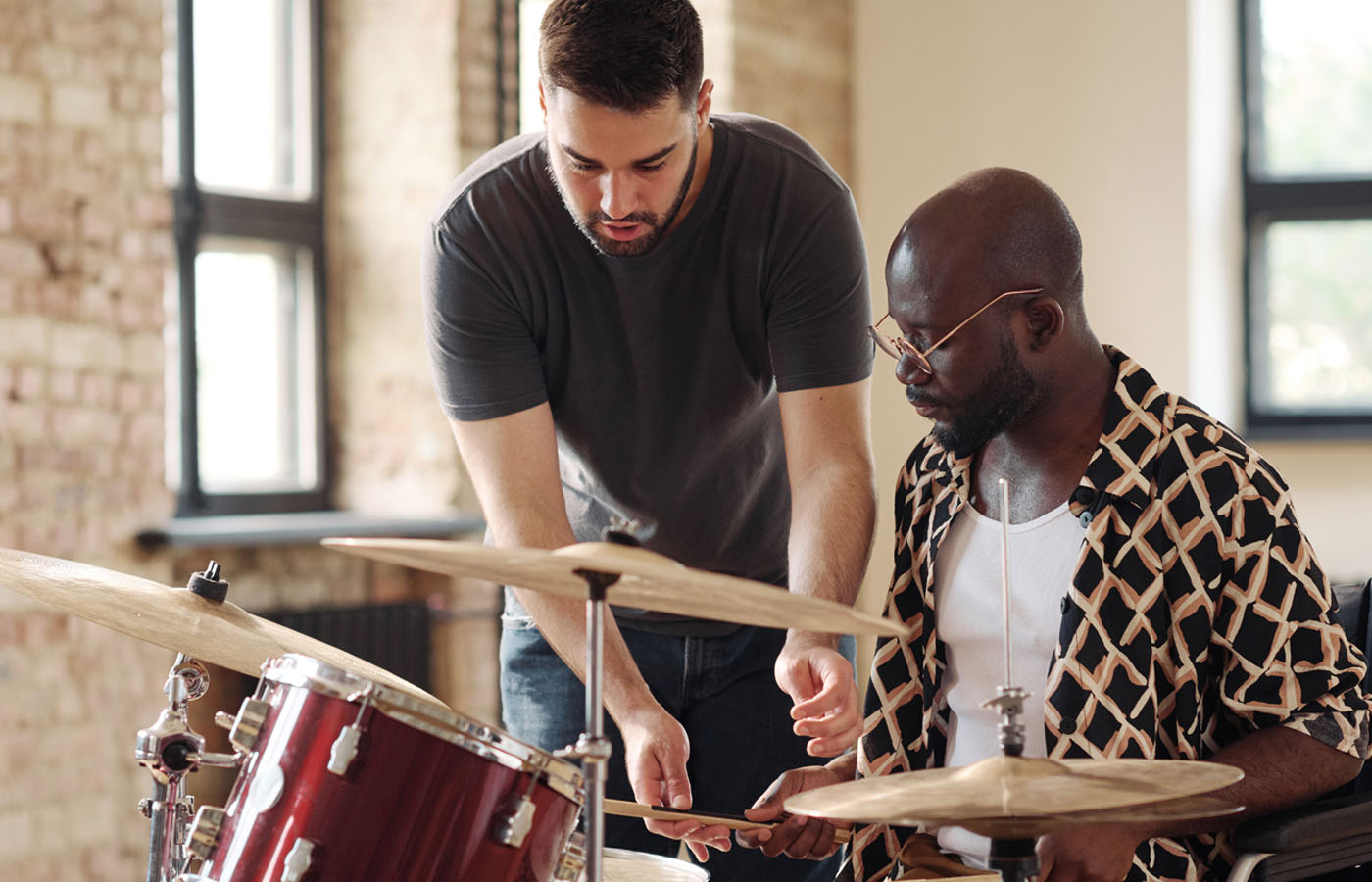A teacher and student playing a drum set during a lesson