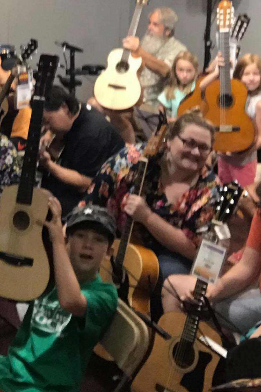 People at a George's Music in-store event holding acoustic guitars.