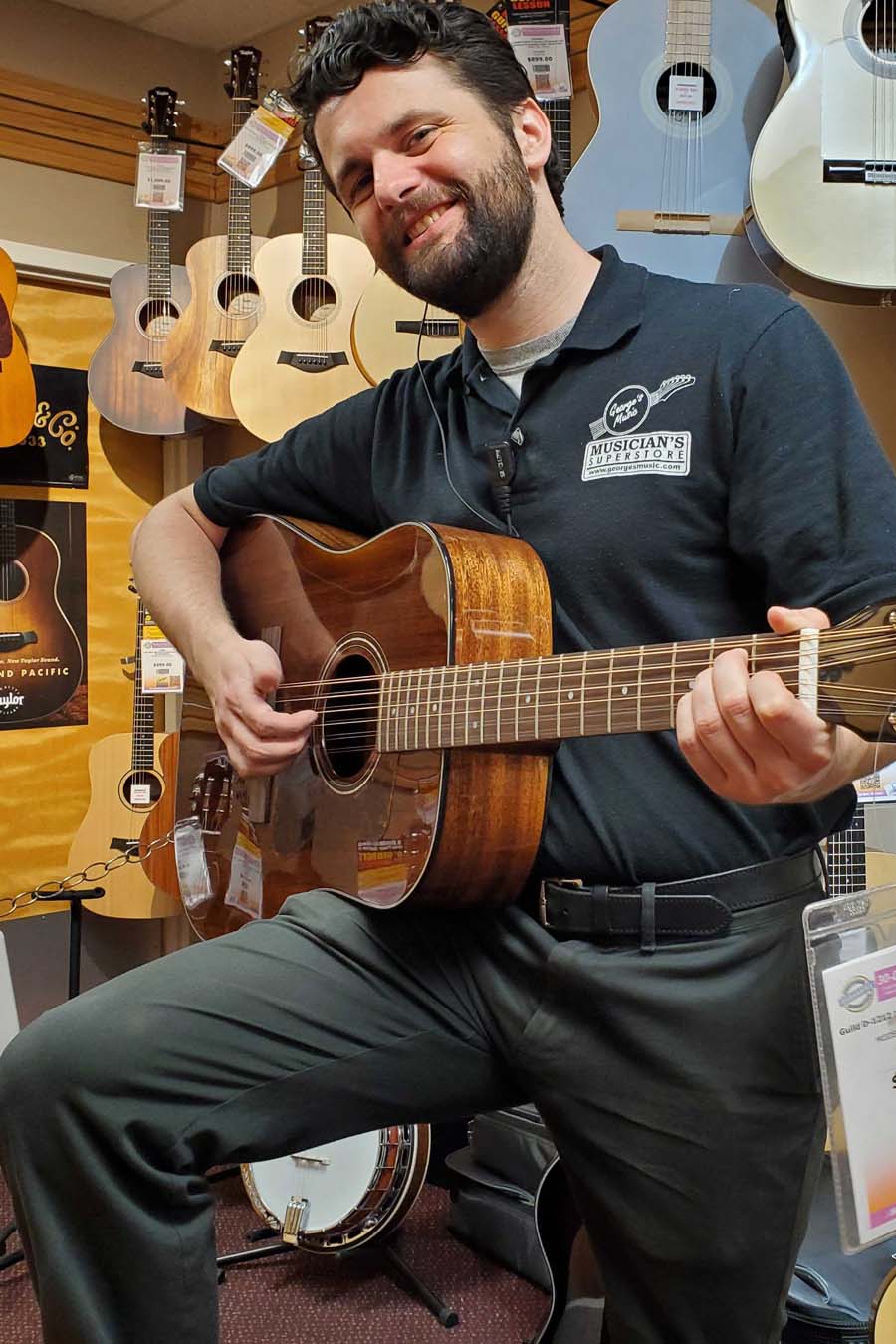 George's Music employee playing an acoustic guitar.