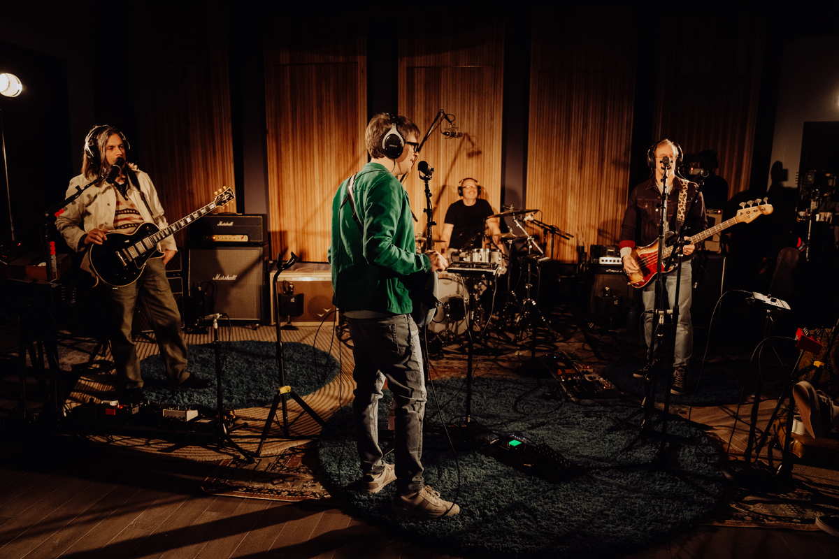 A band in the recording studio promoting Synchrony financing specials for Taylor and Martin guitars